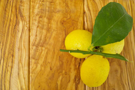 Fresh lemon with leaves on olive wooden background, copy space