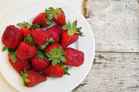 White board with fresh ripe strawberry on rustic wooden background copy spaceの写真素材
