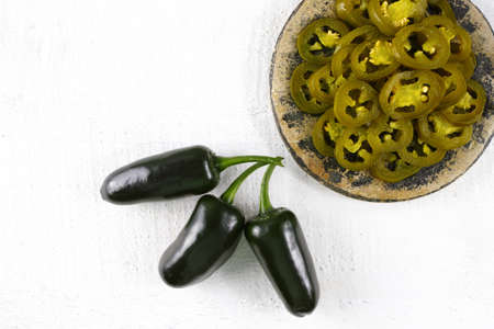 Green fresh and delicious sliced pickled jalapenos on stone with wooden backgroundの写真素材