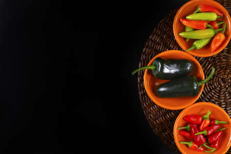 Mexican hot chili peppers colorful mix jalapeno on orange bowls and black backgroundの写真素材