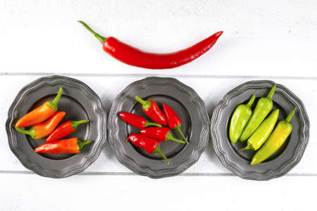Mexican red green orange hot chili peppers colorful mix jalapeno on metal bowlsの写真素材