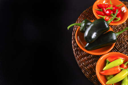 Mexican hot chili peppers colorful mix jalapeno on orange bowls and black backgroundの写真素材
