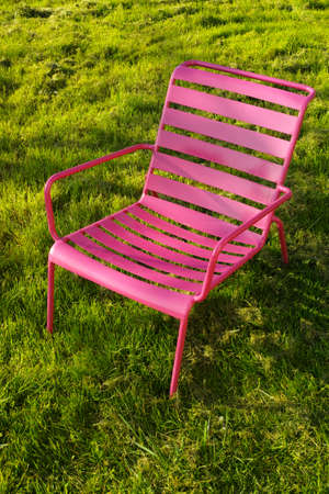 Pink metal relax chair on the green grass in garden