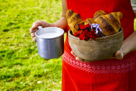 Young woman in red apron holding farm milk and fresh baked croissantsの写真素材