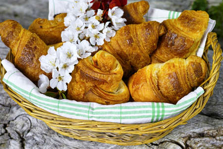Fresh french croissants in a basket from bakery on wooden backgroundの写真素材