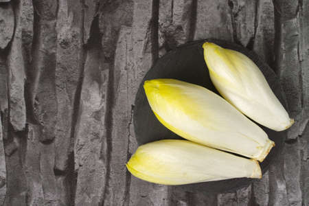 Fresh Chicory Salad leaves placed on a grey stone board copy space