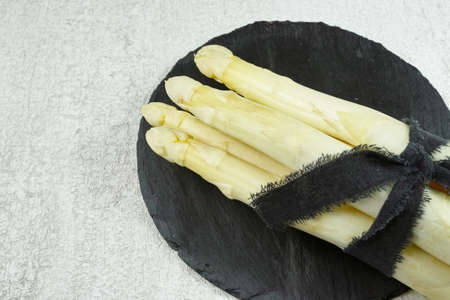 Fresh white asparagus on the black stone board and grey background