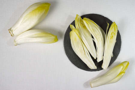 Fresh Chicory Salad leaves placed on a grey stone board on white backgroundの写真素材