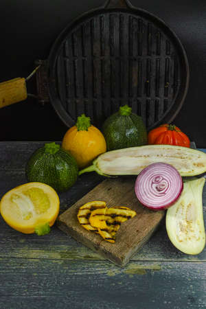 Vegetables for grill - yellow and green zucchini, red onion, eggplant and grill pan on dark backgroundの写真素材
