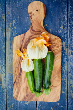 Flowering and ripe zucchini on deep blue wooden backgroundの写真素材