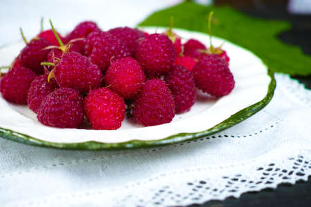 Ripe fresh organic raspberries on white plate and linen white napkinの写真素材