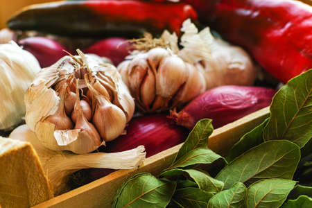 Garlic, pink onion and bay leaf in wooden box on the summer vegetables market in Italyの写真素材