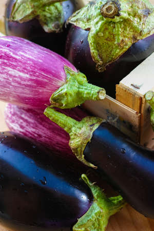 Eggplants of different color and variety in wooden box on the tableの写真素材