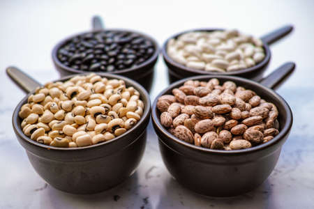 Beans variety/ different types of beans in ceramoc bowls on black wooden background
