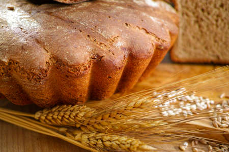Freshly baked sourdough spelt bread on olive wood board with whole grains