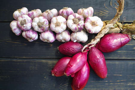 Pink italian onion and garlic braid on black wooden backgroundの写真素材