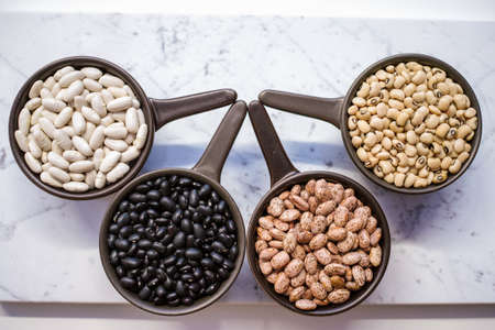 Beans variety/ different types of beans in ceramoc bowls on black wooden backgroundの写真素材