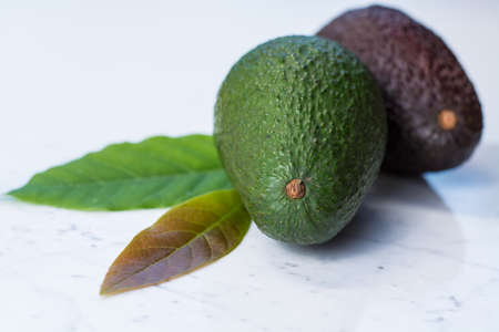 Green ripe avocado on white marble backgroundの写真素材