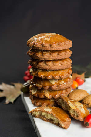 Typical Dutch filled spicy  cookies with almonds on autumn colored and dark backgroundの写真素材