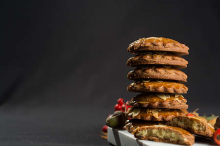 Typical Dutch filled spicy  cookies with almonds on autumn colored and dark backgroundの写真素材