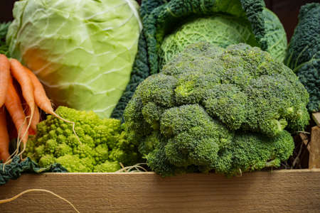 Green and orange fresh vegetables in wooden box, harvest - broccoli, savoy cabbage, green cauliflower, carrot, pumpkinの写真素材