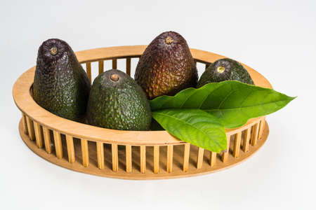 Green fresh avocado with leaves on wooden background isolatedの写真素材