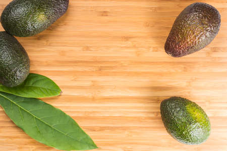 Green fresh avocado with leaves on wooden backgroundの写真素材