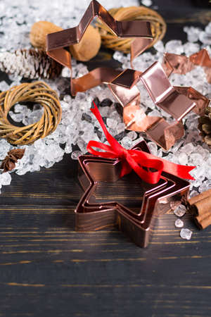 Christmas cookies - copper star-shaped cookies cutters on white ice with red ribbonの写真素材