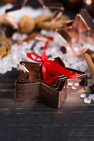 Christmas cookies - copper star-shaped cookies cutters on white ice with red ribbonの写真素材