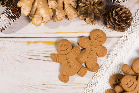 Christmas smiling  gingerbread men, men and women  on white handmade lace with Christmas decorationの写真素材