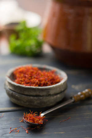 Raw Organic Red Saffron Spice in a clay bowl on wooden tableの写真素材