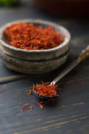 Raw Organic Red Saffron Spice in a clay bowl on wooden tableの写真素材