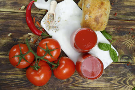 Raw Organic Tomato Juice with salt, basil and bread on wooden backgroundの写真素材