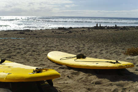 Surf school - several surfboarding students headed into an ocean swell on Tenerife, Spain