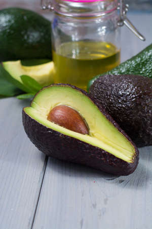 Green ripe fresh avocado with leaves whole and sliced and avocado oil
