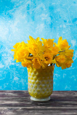 Bright yellow Narcissus flowers bouquet in a yellow glass vase, Easter and spring concept, copy spaceの写真素材