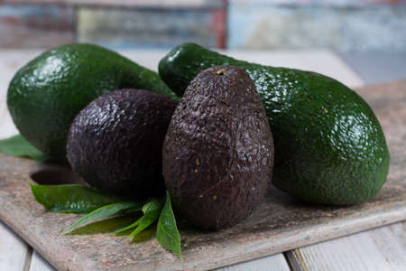 Green ripe fresh avocado with leaves on granite plankの写真素材