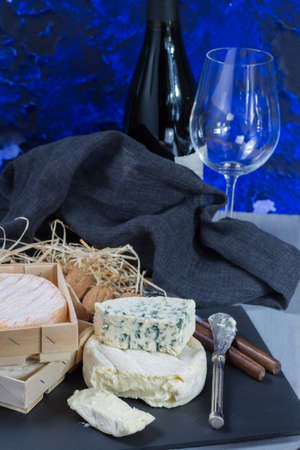 French soft cheeses on black stone platter and bottle with red wineの写真素材