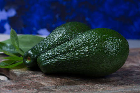 Green ripe fresh avocado with leaves on granite plankの写真素材
