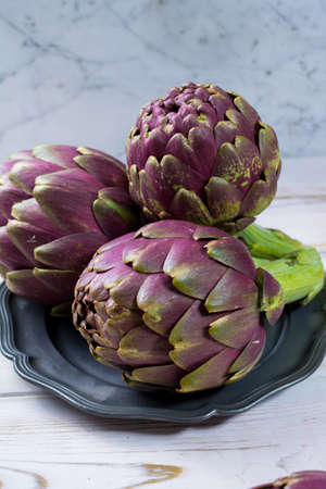 Fresh big Romanesco artichokes green-purple flower heads ready to cook seasonal foodの写真素材