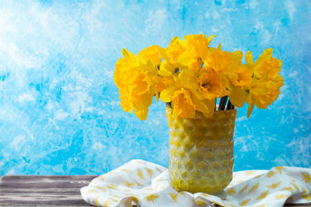Bright yellow Narcissus flowers bouquet in a yellow glass vase, Easter and spring concept, copy spaceの写真素材