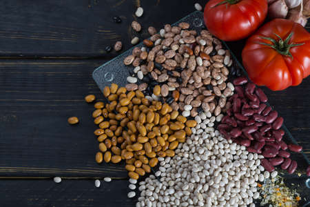 Assortment of beans on black wooden background. Soybean, red kidney bean, black bean,white bean, red bean and brown pinto beansの写真素材
