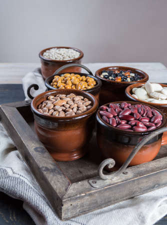 Assortment of beans on black wooden background. Soybean, red kidney bean, black bean,white bean, red bean and brown pinto beansの写真素材