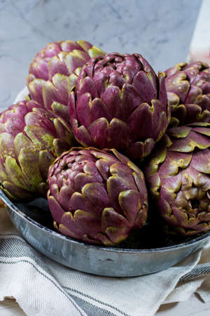 Fresh big Romanesco artichokes green-purple flower heads ready to cook seasonal foodの写真素材