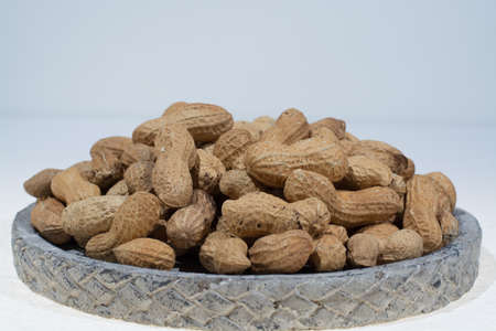 Peanuts in shell on the grey pate, white backgound, copy space