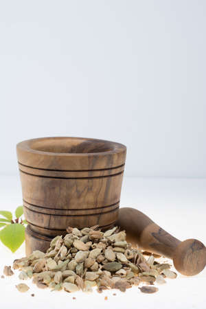 Raw Organic Cardamom Pods Ready to Use with mortar made from olive wood on white, copy spaceの写真素材