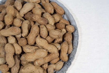 Peanuts in shell on the grey pate, white backgound, copy spaceの写真素材