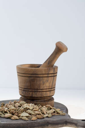 Raw Organic Cardamom Pods Ready to Use with mortar made from olive wood on white, copy spaceの写真素材