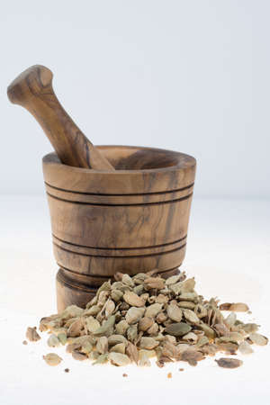 Raw Organic Cardamom Pods Ready to Use with mortar made from olive wood on white, copy spaceの写真素材