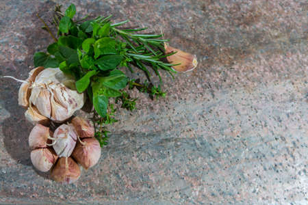 French dried violet garlic and fresh garden herbs on granite plankの写真素材